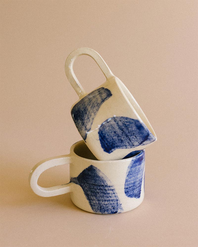 Une tasse en grès avec des motifs bleus faits au pinceau