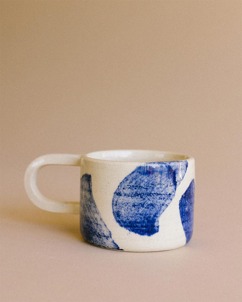 Une tasse en grès avec des motifs bleus faits au pinceau