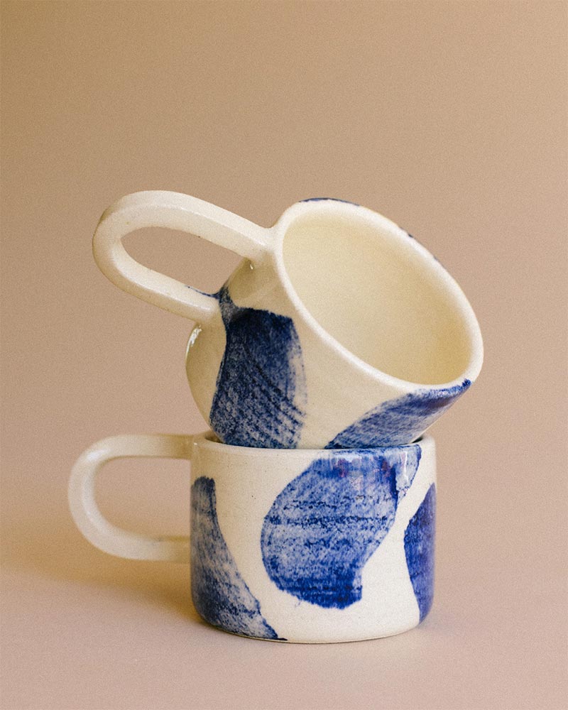 Une tasse en grès avec des motifs bleus faits au pinceau